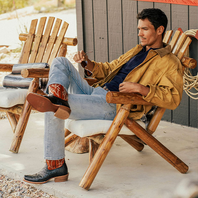 A man sitting on his porch wearing Rylen 13" Full Quill cowboy boots in brown